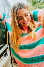 Woman wearing a colorful striped sweater standing next to a car.